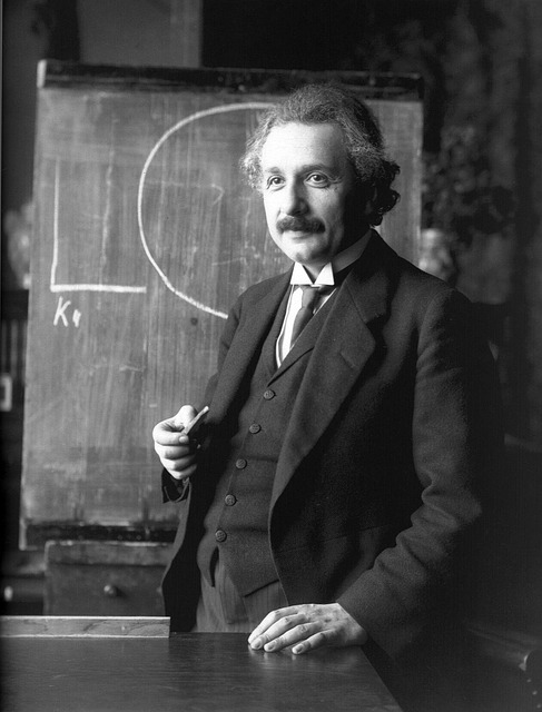 Albert Einstein standing in front of chalkboard